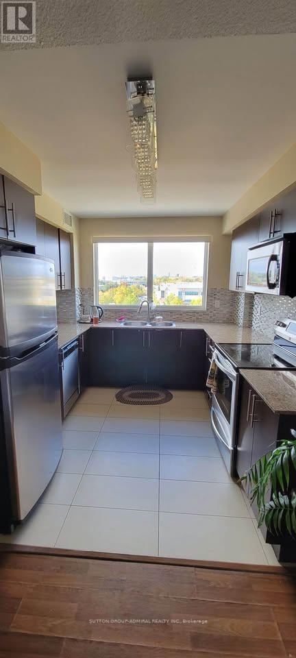 A kitchen with a refrigerator, oven, and sink.