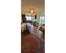 A dining room with a table set for four and a rug on the floor.
