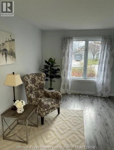 A living room with a chair, a table, and a painting on the wall.