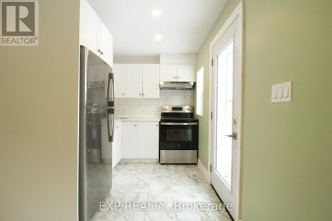 A kitchen with a refrigerator, oven, and microwave.