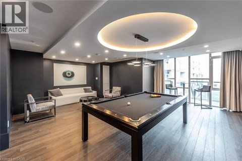 A pool table is in the middle of a living room with a couch and chairs.