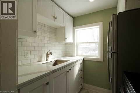 A kitchen with white cabinets and a green wall.
