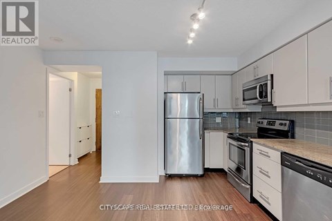 A kitchen with white cabinets and a stainless steel refrigerator.