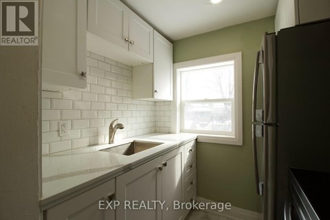 A kitchen with white cabinets and a white sink under a window.