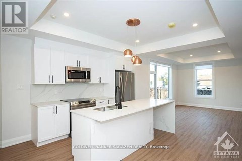 A modern kitchen with white cabinets and a wooden floor.