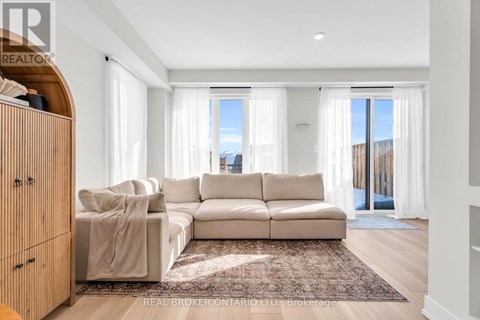 A living room with a white couch and a rug in front of it.