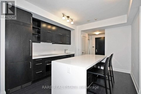 A kitchen with black cabinets and a white island.