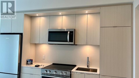 A kitchen with a refrigerator, microwave, and sink.