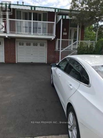 A white car is parked in front of a red brick house.