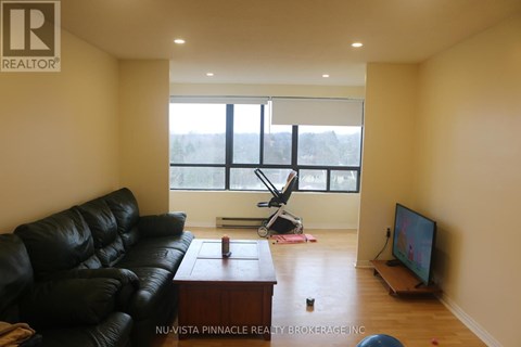 A living room with a black leather couch and a television.