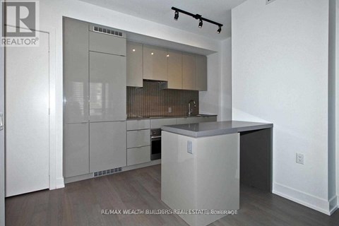 A modern kitchen with white cabinets and a wooden floor.