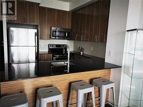 A kitchen with a refrigerator, microwave, and stove.