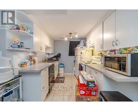 A kitchen with white cabinets and appliances, a rug on the floor, and a box of TJ Maxx on the counter.