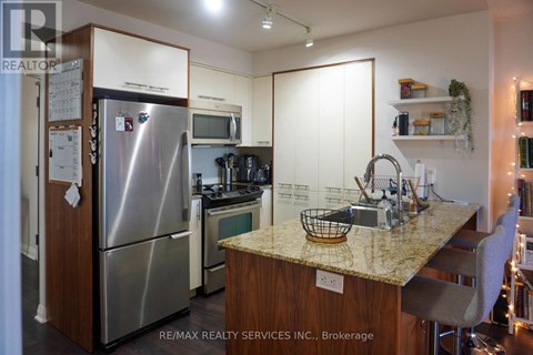 A kitchen with a refrigerator, microwave, oven, and sink.