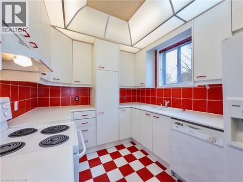 A kitchen with red tiles and white appliances.