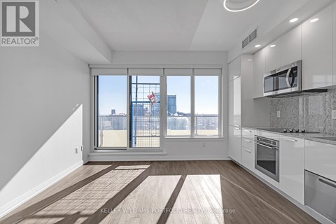 A modern kitchen with white cabinets and a large window overlooking the city.