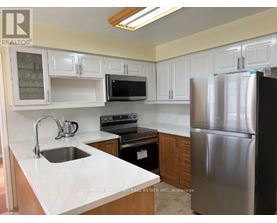 A kitchen with white cabinets and a stainless steel refrigerator.