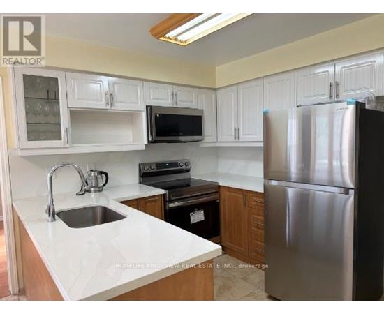 A kitchen with white cabinets and a stainless steel refrigerator.