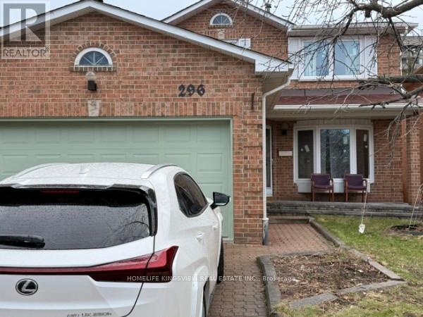 A white Lexus SUV is parked in front of a brick house with the number 296 on it.