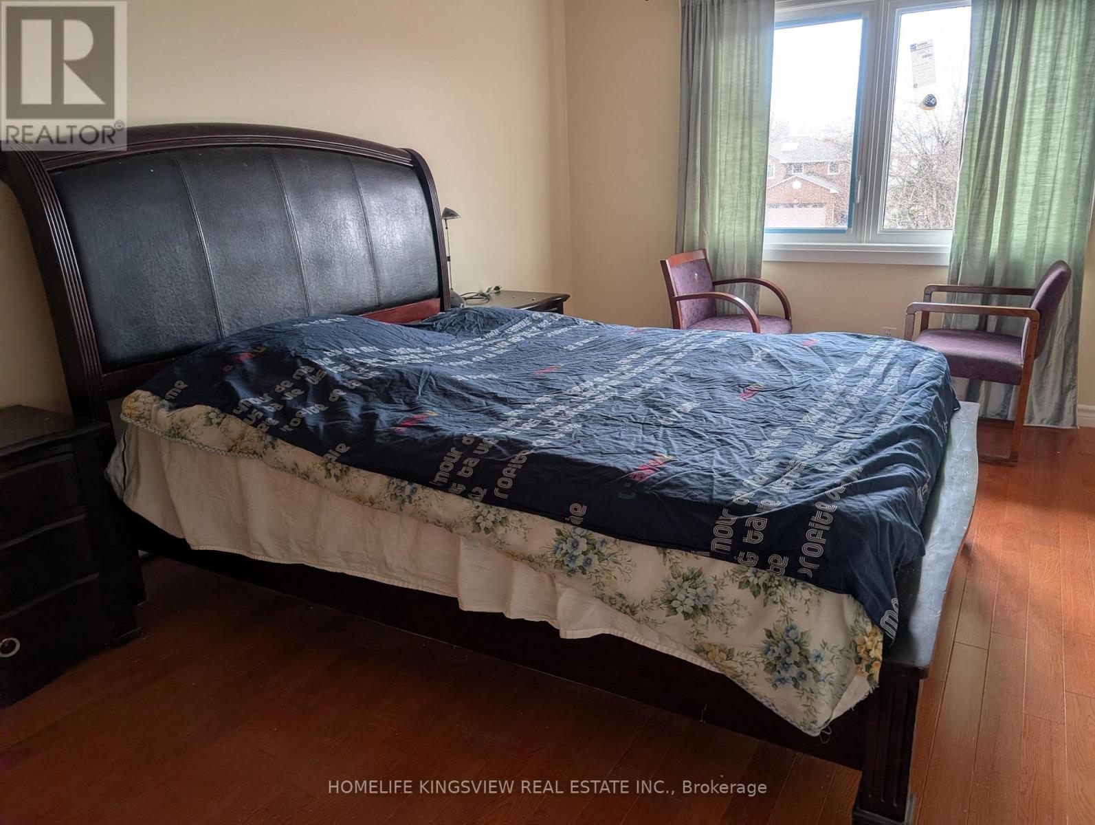 A bedroom with a large bed and a window with green curtains.