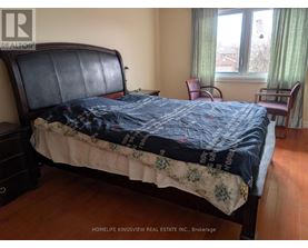 A bedroom with a large bed and a window with green curtains.