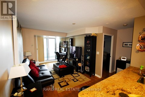 A living room with a black leather couch and a television.
