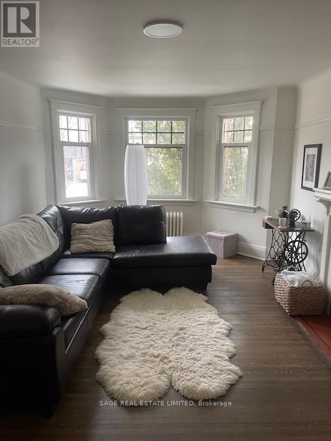 A living room with a black leather couch and a white fluffy rug.