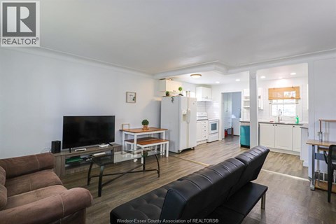 A living room with a couch, a television, and a dining area with a table and chairs.