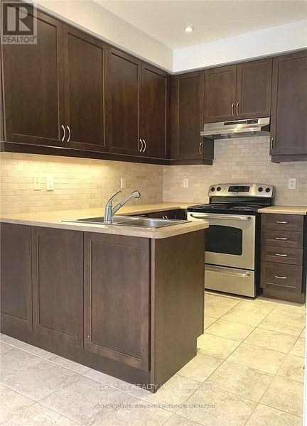 A kitchen with dark wood cabinets and a tile backsplash.