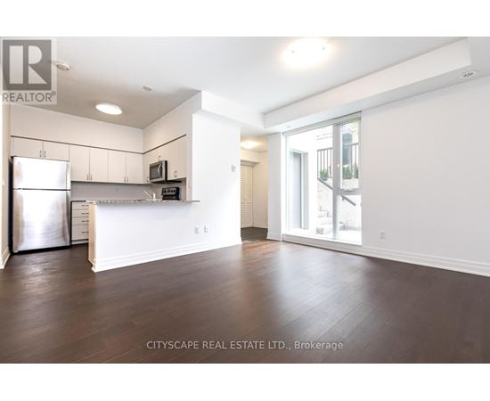 A spacious kitchen with white cabinets and a refrigerator.