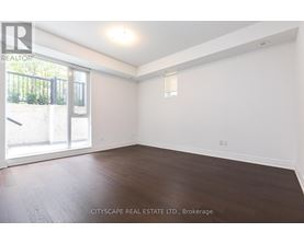A spacious room with wooden floors and a sliding glass door leading to a balcony.