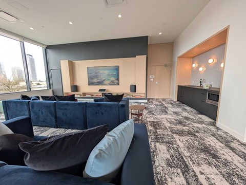 A living room with a dark blue couch and a painting on the wall.