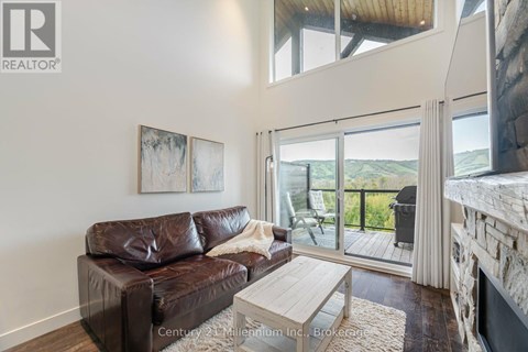 A living room with a brown leather couch and a fireplace.
