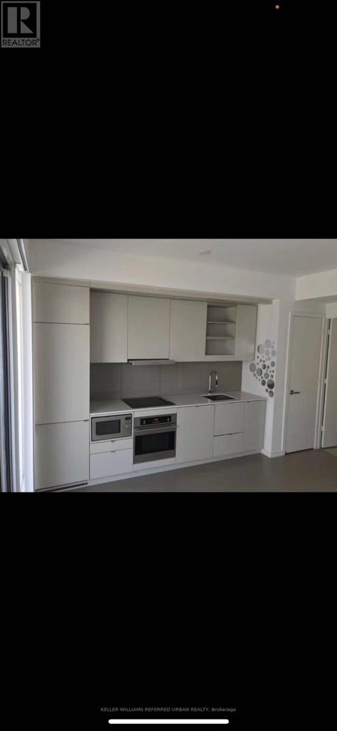 A modern kitchen with white cabinets and a black countertop.