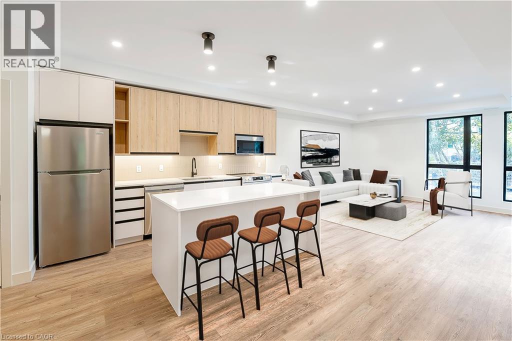 A modern kitchen with a refrigerator, bar stools, and a dining table.