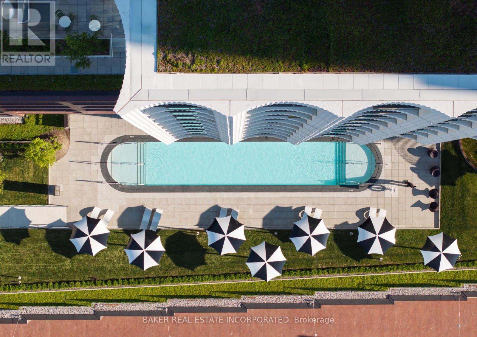 An aerial view of a pool surrounded by umbrellas and a building with the logo "TR" on it.