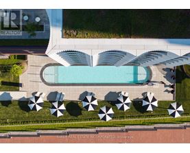 An aerial view of a pool surrounded by umbrellas and a building with the logo "TR" on it.