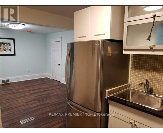 A kitchen with a stainless steel refrigerator and wooden flooring.