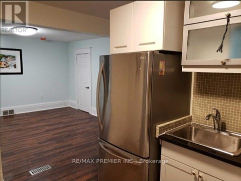 A kitchen with a stainless steel refrigerator and wooden flooring.
