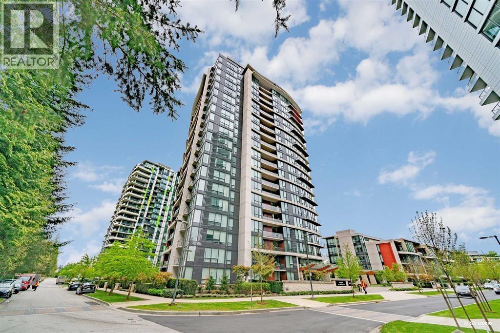 A tall residential building with a glass facade stands in the foreground of a sunny street.
