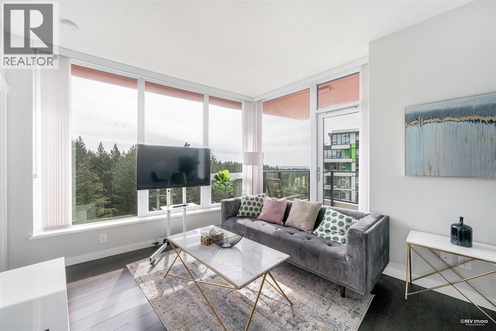 A living room with a grey couch and a large window.
