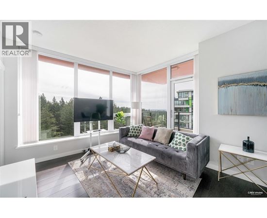 A living room with a grey couch and a large window.
