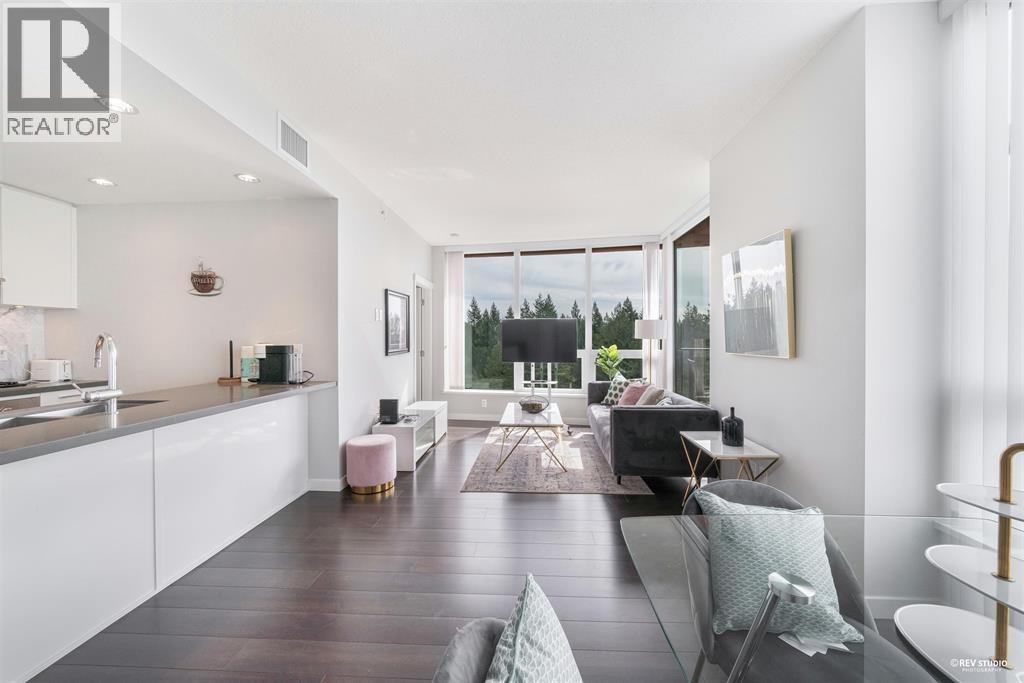 A modern living room with a kitchen area in the background.