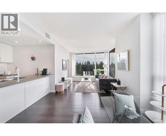 A modern living room with a kitchen area in the background.