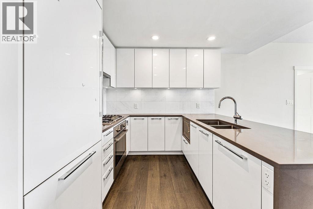 A modern kitchen with white cabinets and a wooden floor.