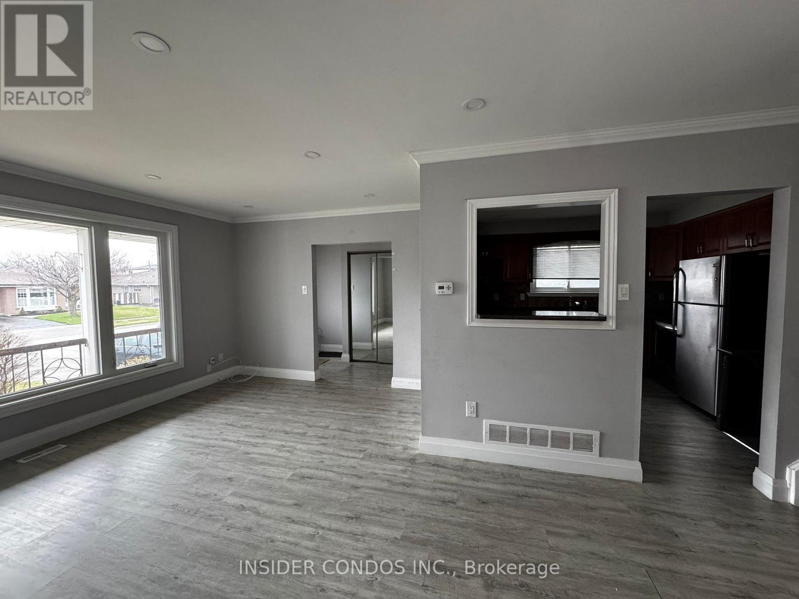 A spacious room with a large window and a door leading to another room.