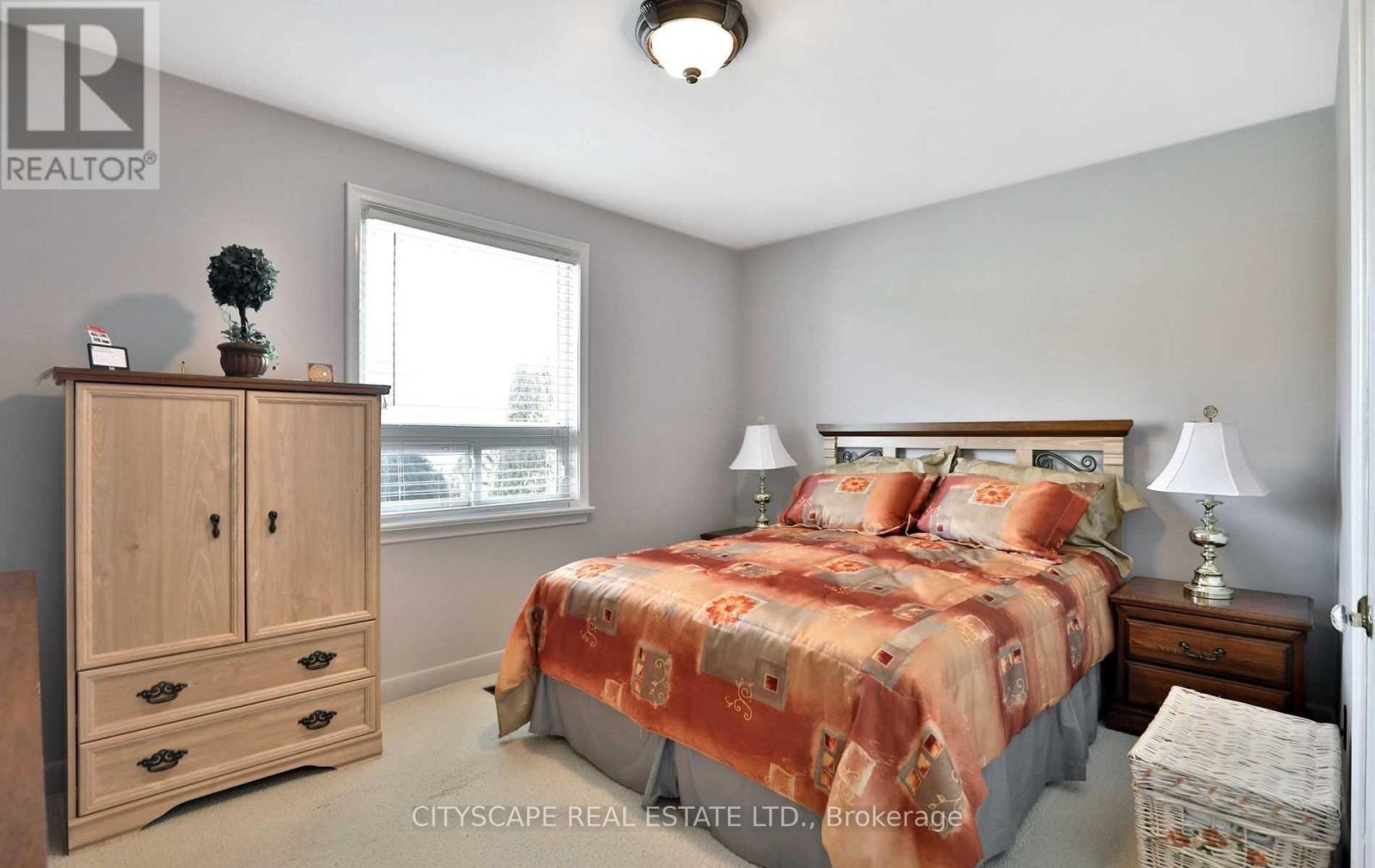 A bedroom with a bed, nightstand, and a wooden armoire.