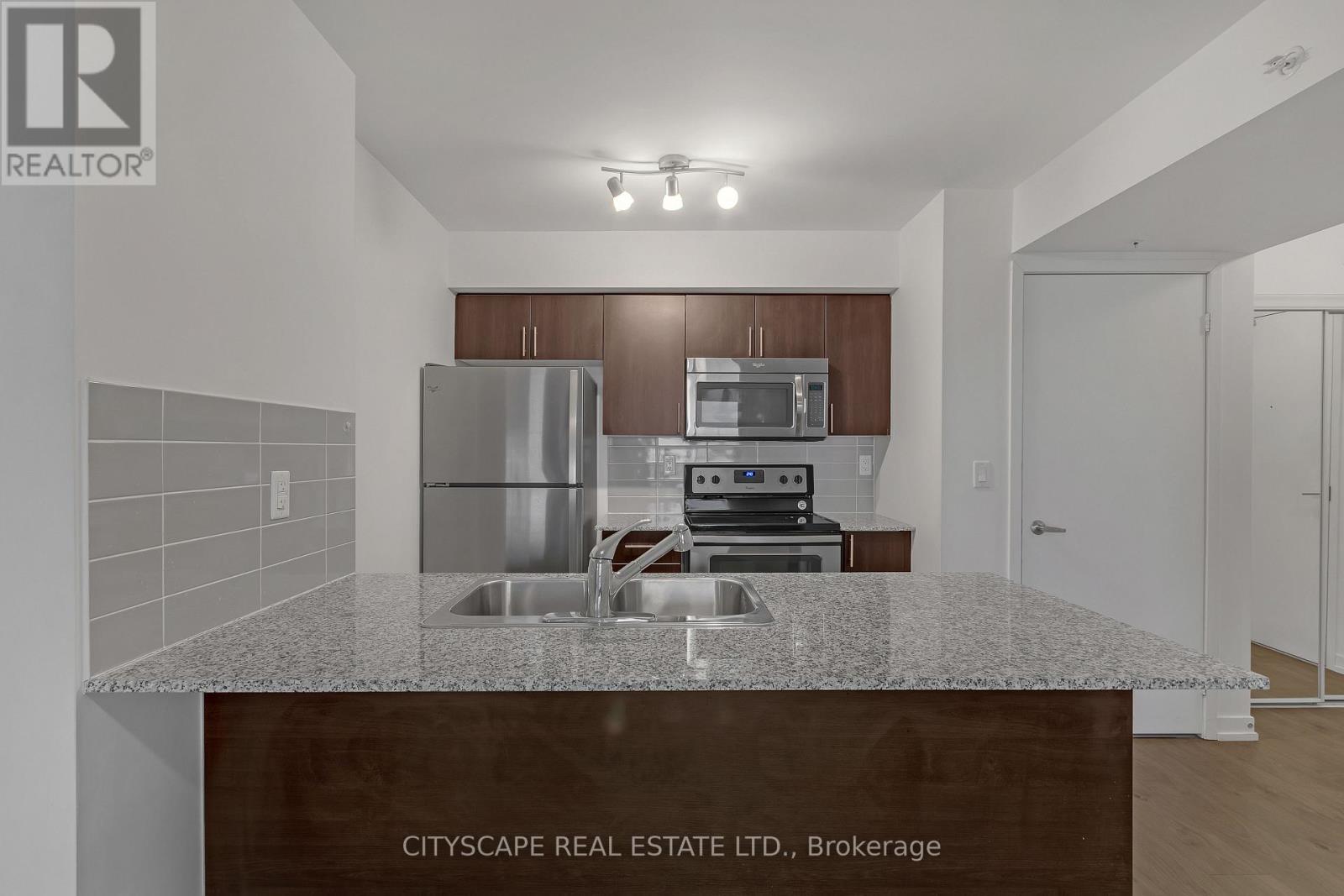 A kitchen with a granite countertop and stainless steel appliances.