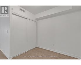 A white bedroom with a sliding door closet and a realtor sign on the wall.