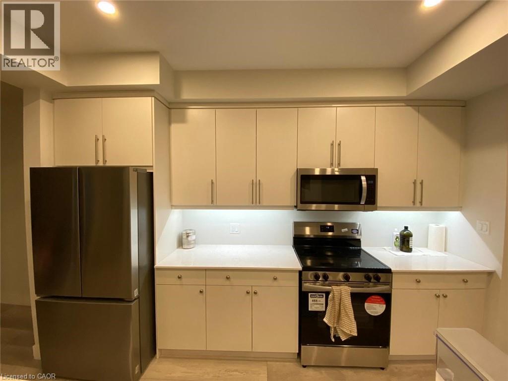 A kitchen with a refrigerator, stove, and microwave.